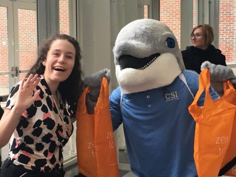 Bagdrive CSI's mascot Danny the dolphin is standing with visitor holding an orange reusable bag