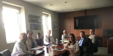 Daylight Hour Picture of President's office cabinet sitting around oval table with the shades up letting daylight in.