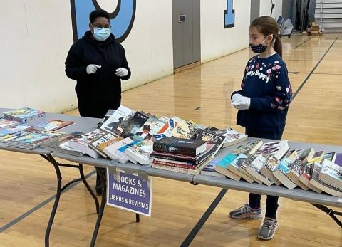 Books on tables at the Stop and Swap event 2 kids standing next to tables with books